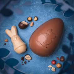 an easter egg, chocolate and nuts on a blue plate with leaves in the background