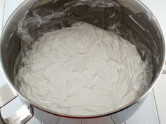 a large metal pot filled with white frosting on top of a stove burner