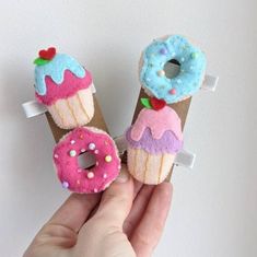 two donuts with sprinkles and frosting on them are being held by a hand