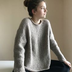 a woman sitting on top of a chair wearing a sweater