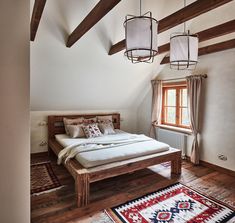 a bed sitting in the middle of a bedroom next to a window with two lamps hanging above it