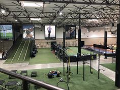 an indoor tennis court with equipment and people on the sidelines in front of large screens