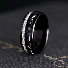 black ceramic ring with silver glitter inlays on the outside and inside, sitting on a dark surface