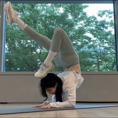 a woman is doing a yoga pose on the floor in front of a large window