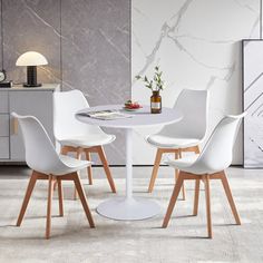 three white chairs around a round table in a room with marble walls and flooring