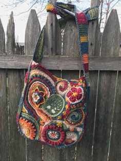 a crocheted purse hanging on a wooden fence