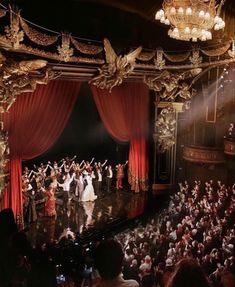 a group of people standing on top of a stage in front of a red curtain