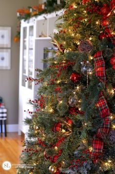 the christmas tree is decorated with red and silver ornaments, plaid bows and pine cones