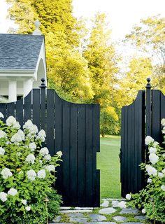 an open black gate with white flowers in the foreground