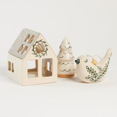 three ceramic figurines in the shape of houses and trees on a white background