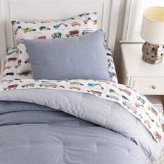 a bed with blue comforter and pillows on top of it next to a night stand