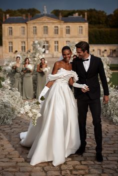 a bride and groom are walking down the aisle at their wedding ceremony in front of an elegant mansion