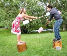 two people are playing with jugs in the grass and one person is on a stump