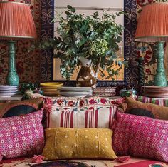 a living room filled with lots of colorful pillows and lamps on top of a table