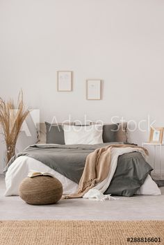 a bedroom with white walls and grey bedding, rugs and pictures on the wall