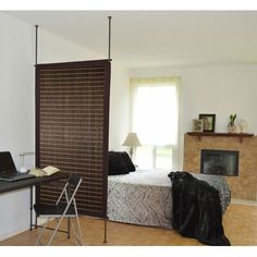 a bedroom with a bed, desk and chair next to a fire place in the corner