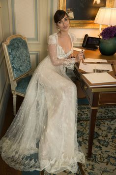 a woman in a white dress sitting at a desk