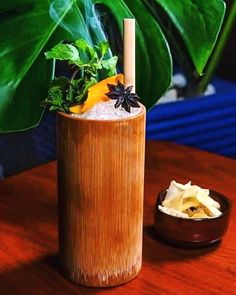 a tall wooden cup sitting on top of a table next to a bowl filled with food