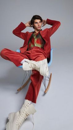 a man sitting in a rocking chair with his hands on his head and legs crossed