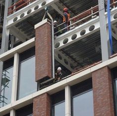 two men working on the side of a tall building