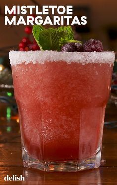 a close up of a drink in a glass with ice and berries on the rim