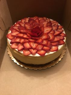 there is a cake with strawberries on it in the box and ready to be eaten