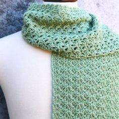 a green crocheted scarf on top of a mannequin