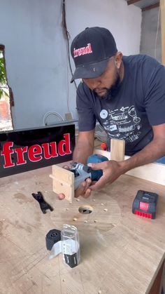 a man sanding wood on top of a wooden table next to tools and a sign