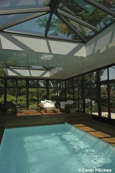 an indoor swimming pool in the middle of a patio area with glass walls and ceiling