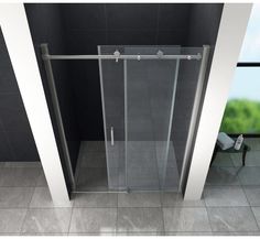 a glass shower door in a bathroom with tile flooring and gray wall tiles on the walls