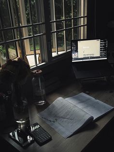 an open book sitting on top of a desk next to a computer monitor and keyboard