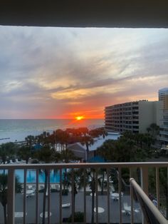 the sun is setting over the ocean from an apartment balcony