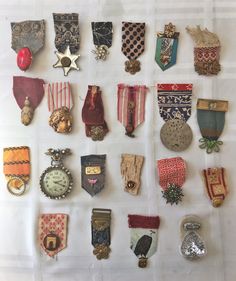 an assortment of medals and badges are displayed on a white sheeted surface in front of a wall