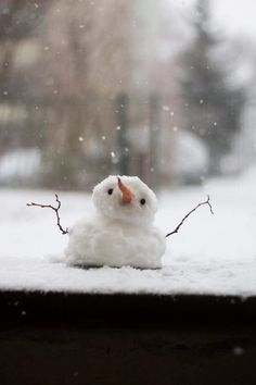 a snowman with an orange nose is sitting in the window sill and looking out