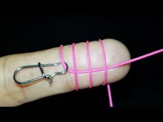 a hand holding a pink string with a pair of scissors on it's end