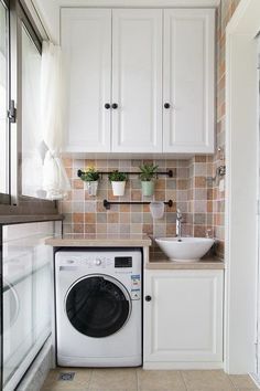 a washer and dryer in a small room with white cabinets on the wall