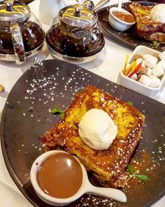 french toast with ice cream and chocolate sauce on a black plate next to other desserts