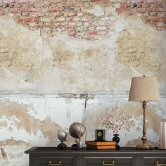 a dresser with two lamps on top of it next to a brick wall