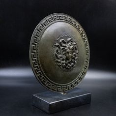 a bronze plate with a lion head on it's face is shown in front of a black background