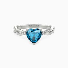 a heart shaped blue topazte ring with white diamonds on the sides and shoulders