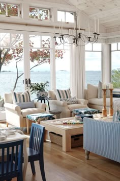 a living room filled with lots of furniture and large windows overlooking the ocean on a sunny day