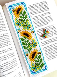 cross stitch bookmark with sunflowers and butterflies on the front, in an open book