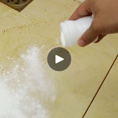 a person is using a bottle to disinfectate white stuff on a wooden surface