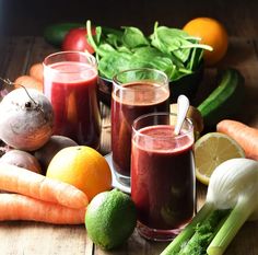 there are many fruits and vegetables on the table with juices in front of them