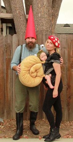 a man and woman dressed up as gnomes with a baby in a sleeping bag