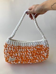 an orange and white basket is being held by a woman's hand on a white surface