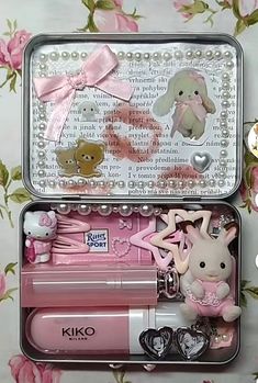 an open tin box filled with lots of pink stuff animals and other things in it