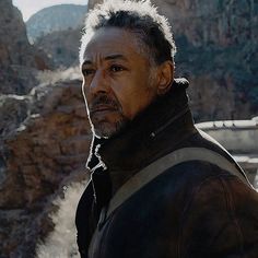 a man standing in front of a mountain with mountains in the backgrouds