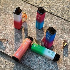 four different colored lighters sitting on top of a stone floor next to each other