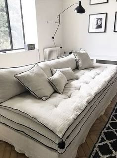 a white couch sitting on top of a hard wood floor next to a black and white rug